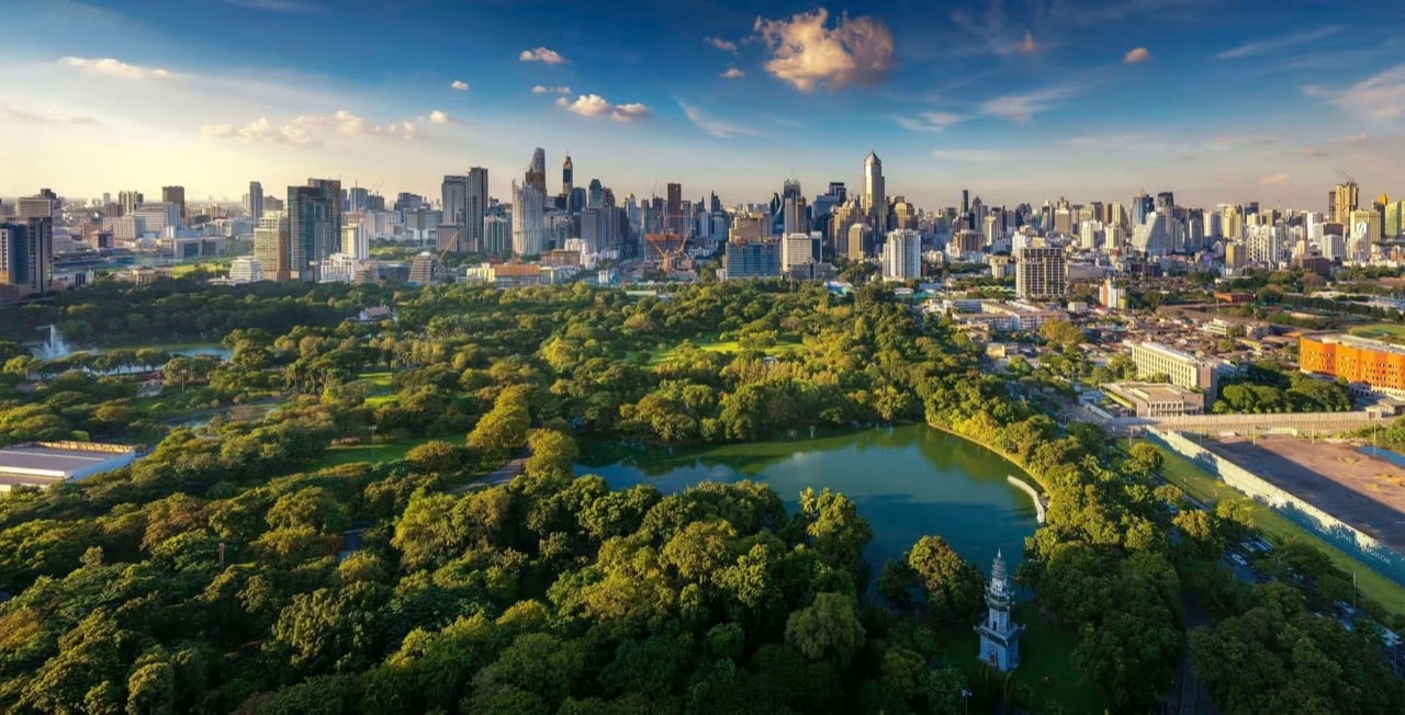 Lumphini Park’s lake and tree canopy with central Bangkok’s skyline beyond